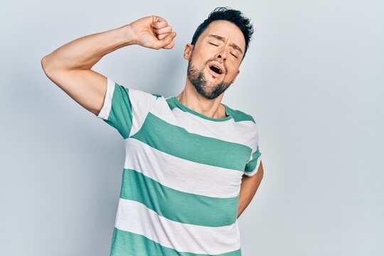 Young hispanic man wearing casual clothes stretching back, tired and relaxed, sleepy and yawning for early morning