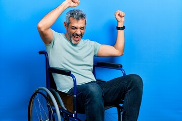 Handsome middle age man with grey hair sitting on wheelchair dancing happy and cheerful, smiling moving casual and confident listening to music