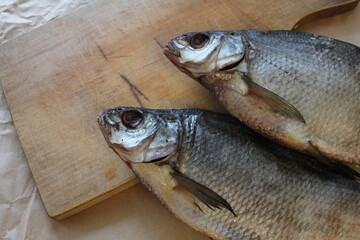 Two large dried bream for beer lie on a wooden board on craft paper