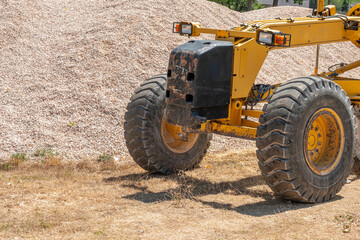 Grader in front of a pile of gravel