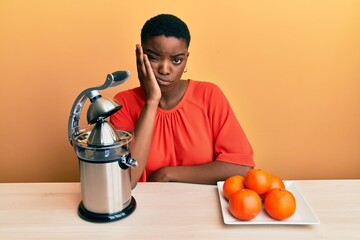 Young african american woman sitting on the table using juicer thinking looking tired and bored with depression problems with crossed arms. - Powered by Adobe