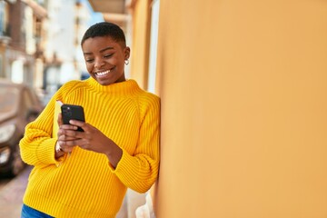 Young african american woman smiling happy using smartphone at the city