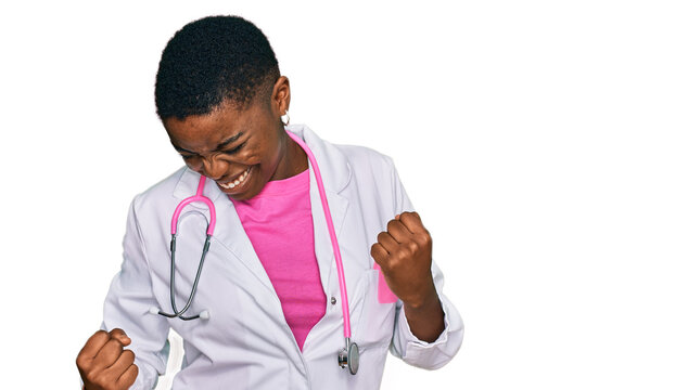 Young african american woman wearing doctor uniform and stethoscope very happy and excited doing winner gesture with arms raised, smiling and screaming for success. celebration concept.