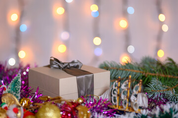 Christmas gift box decorated with tinsel on the background of a sparkling garland.