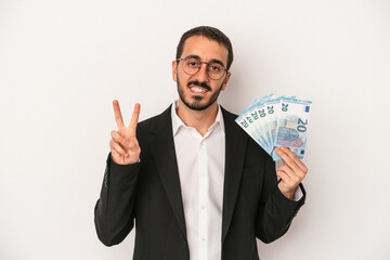 Young caucasian business man holding banknotes isolated on white background showing number two with fingers.