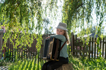 girl playing the accordion in the autumn park. autumn accordion. girl doing music. child in the...