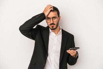 Young business man holding a mobile phone isolated on white background being shocked, she has...