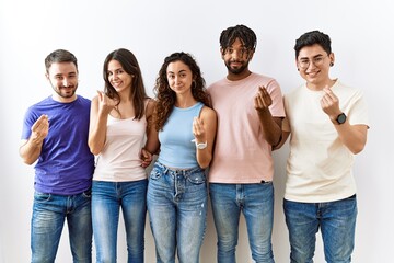 Obraz premium Group of young people standing together over isolated background doing money gesture with hands, asking for salary payment, millionaire business