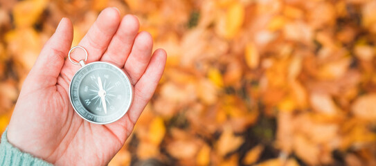 Compass lay on hand in the autumn forest. Selective focus. Shot from above. Point of view.