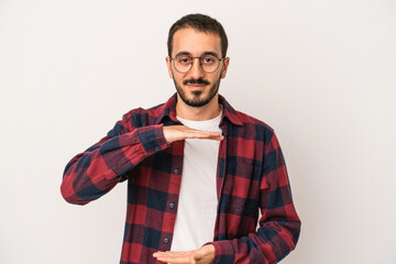 Young caucasian man isolated on white background holding something with both hands, product presentation.