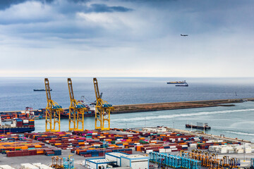 Puerto de mercancías de Barcelona, con barcos y avión aproximándose al aeropuerto.