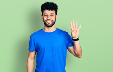 Young arab man with beard wearing casual blue t shirt showing and pointing up with fingers number four while smiling confident and happy.