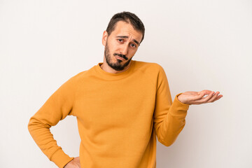 Young caucasian man isolated on white background doubting and shrugging shoulders in questioning...