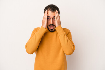 Young caucasian man isolated on white background having fun covering half of face with palm.