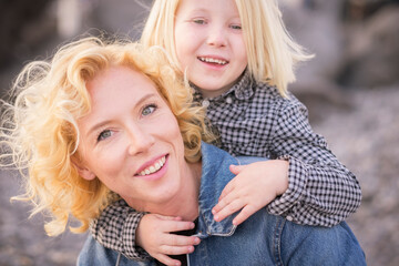 Cheerful and happy mother with son having fun together. Mom carrying his little boy on her shoulder...