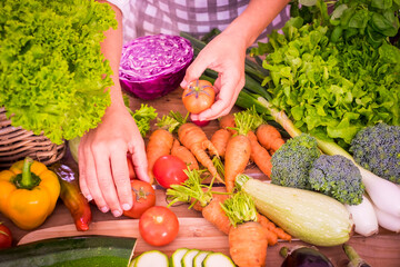 High angle view of fresh vegetables on kitchen counter while chef holding fresh tomatoes in hand. Healthy organic vegetables on kitchen countertop. Vegan options available for dinner..