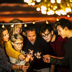 Family celebrating holding burning sparkles. Men and women having fun together. Parents with...