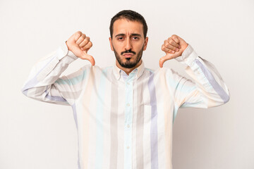 Young caucasian man isolated on white background showing a dislike gesture, thumbs down....