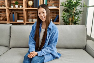 Obraz premium Young chinese girl smiling happy sitting on the sofa at home.