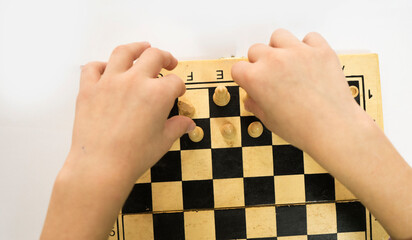 One person arranges white chess pieces on a wooden board. Brain-developing games