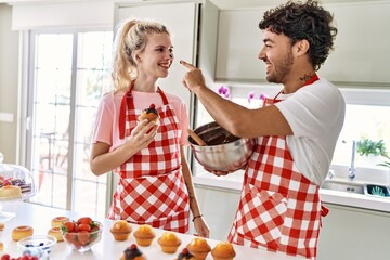 Young couple smiling happy playing with chocolate at kitchen.