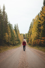 Man aged 23 wearing a checked red and black shirt walks along a foamy path surrounded by beautiful deciduous trees coloured in autumn colours. Enjoy the moment. Kainuu region, Finland