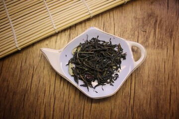 atmosphere Loose dried black tea leaves on plate on wooden background with bamboo