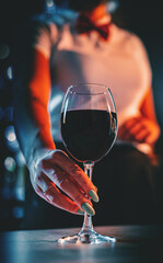 waiter hold red wine into a glass in cafe or bar