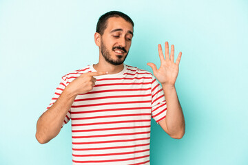 Fototapeta premium Young caucasian man isolated on blue background smiling cheerful showing number five with fingers.