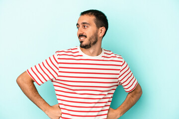 Young caucasian man isolated on blue background laughs happily and has fun keeping hands on stomach.