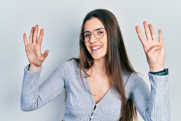 Young brunette teenager wearing casual sweater and glasses showing and pointing up with fingers...