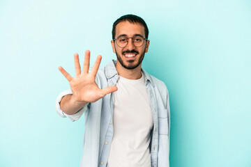 Fototapeta premium Young caucasian man isolated on blue background smiling cheerful showing number five with fingers.