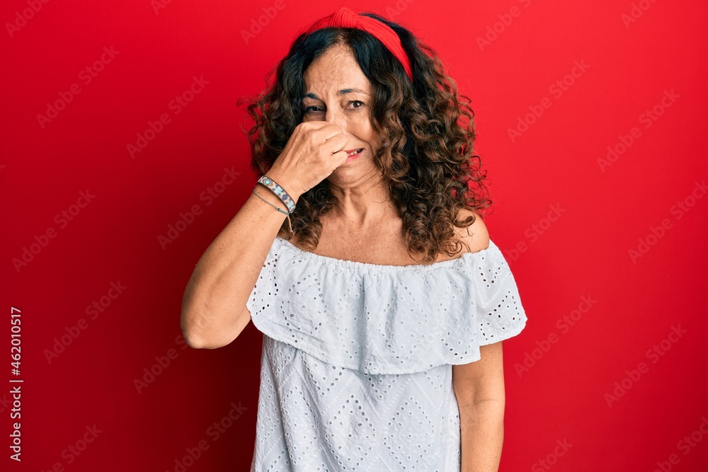 Canvas Prints Middle age hispanic woman wearing casual clothes smelling something stinky and disgusting, intolerable smell, holding breath with fingers on nose. bad smell