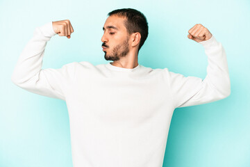 Young caucasian man isolated on blue background showing strength gesture with arms, symbol of feminine power