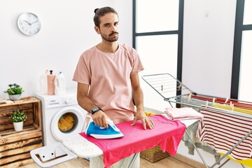 Obraz premium Young hispanic man ironing clothes at home skeptic and nervous, frowning upset because of problem. negative person.