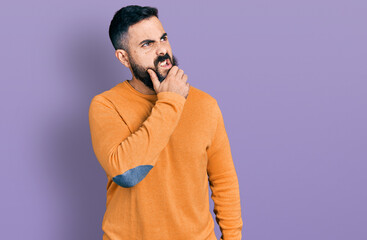 Fototapeta premium Hispanic man with beard wearing casual winter sweater thinking worried about a question, concerned and nervous with hand on chin