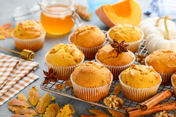 Spicy pumpkin muffins or cupcakes with walnuts on a metal rack. Autumn dessert. Selective focus 