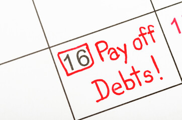 The words Pay off debts written on a calendar
