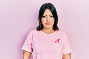 Fototapeta premium Young hispanic woman wearing pink cancer ribbon on t shirt skeptic and nervous, frowning upset because of problem. negative person.