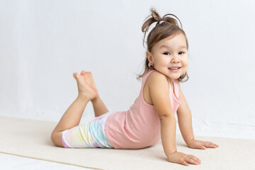 Little asian girl practices yoga asana bhujangasana. Cobra pose.