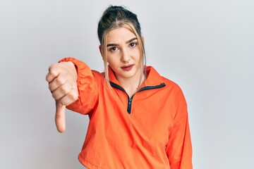 Young modern girl wearing sports sweatshirt looking unhappy and angry showing rejection and negative with thumbs down gesture. bad expression.