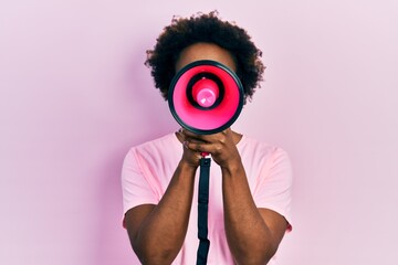African american woman with afro hair screaming with megaphone over pink background - obrazy, fototapety, plakaty