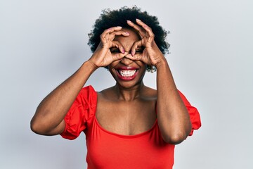 Young african american woman wearing casual clothes doing ok gesture like binoculars sticking tongue out, eyes looking through fingers. crazy expression.