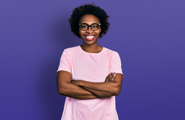 African american woman with afro hair wearing casual clothes and glasses happy face smiling with crossed arms looking at the camera. positive person.
