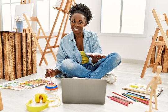 Young african american artist woman using laptop drawing at art studio.