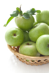 Juicy green apples on a white table with wicker stand