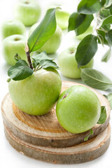 Juicy green apples on a white table with wicker stand