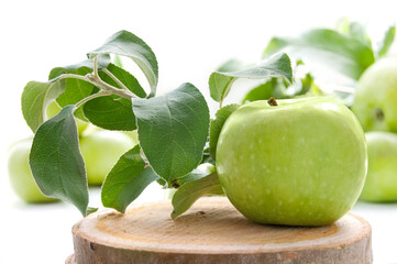 Juicy green apples on a white table with wicker stand