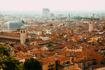 Fototapeta na wymiar Aerial view of the historical center of Brescia (Lombardy, Italy) with red tile roofs, chimneys, cathedral's domes and tall white brick old towers. Traditional European medieval architecture.