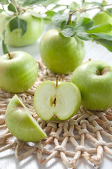 Juicy green apples on a white table with wicker stand